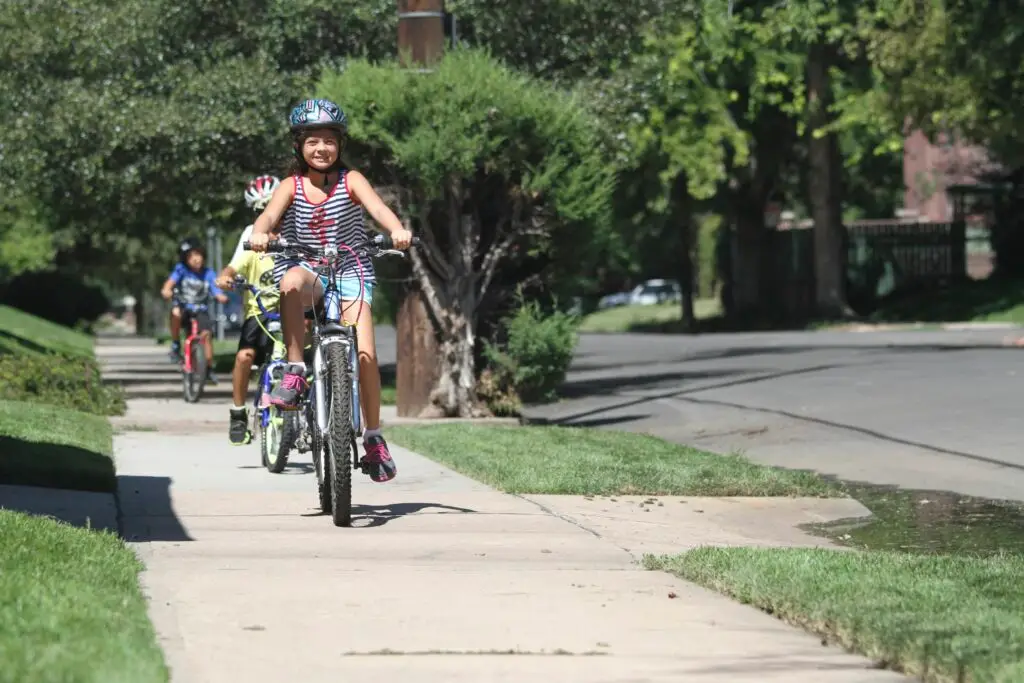 Youth bicyclists ride on the sidewalk