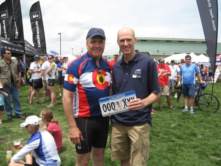 Two men hold Share the Road license plate