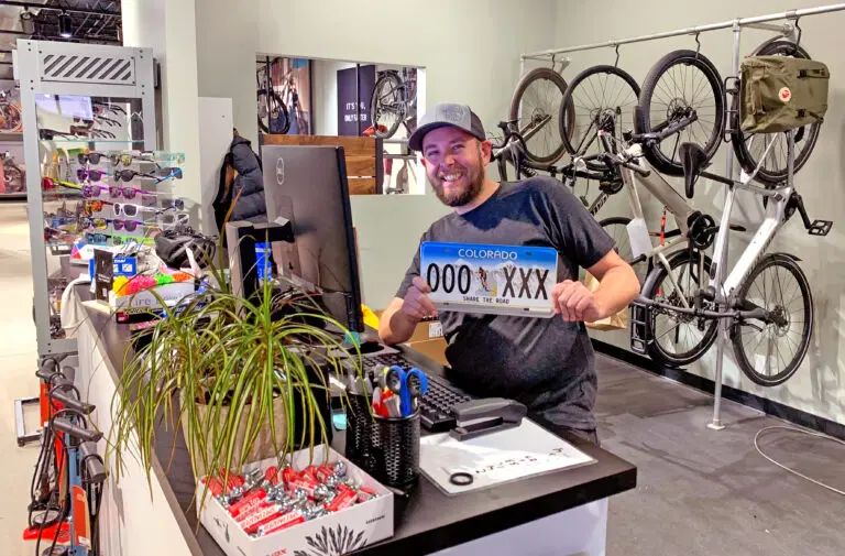 Bike shop employee holding a Share the Road license plate