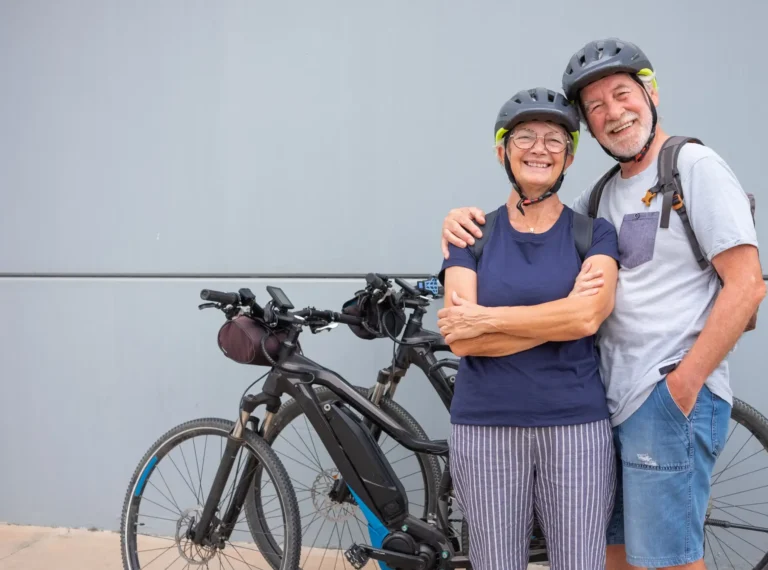 Senior e-bike riders stand with their bikes.