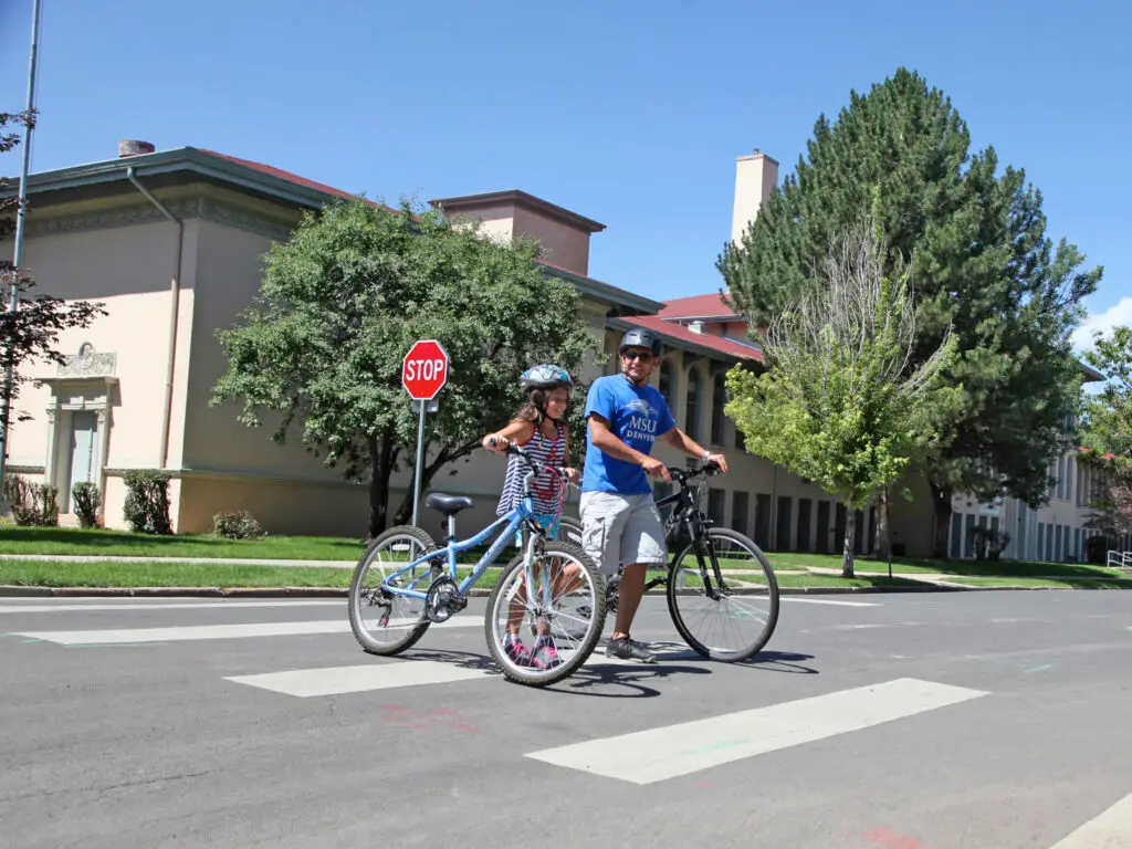 Bicyclists walk their bike in a crosswalk
